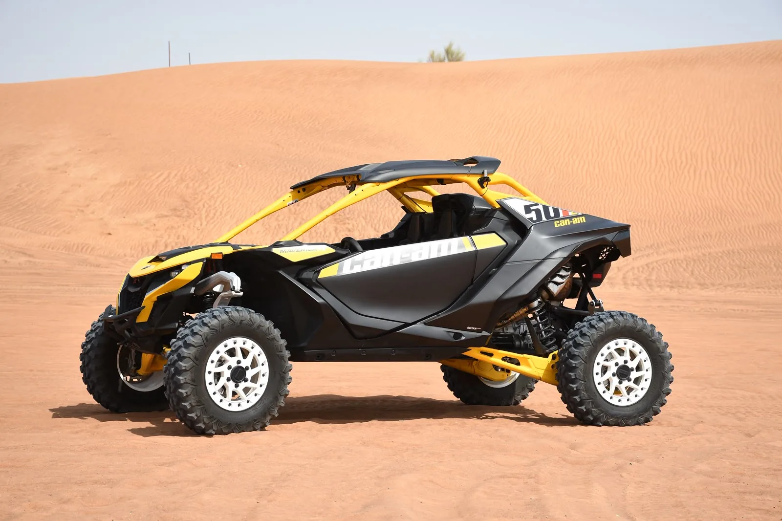 Yellow Can-Am Maverick R turbo dune buggy on the red dunes at Lahbab, Dubai