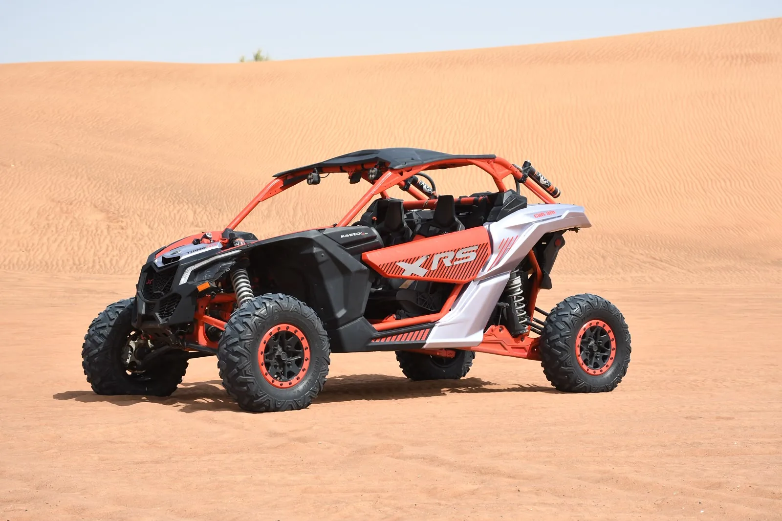 Red and white Can-Am Maverick X3 X RS turbo two seater on Dubai desert sand