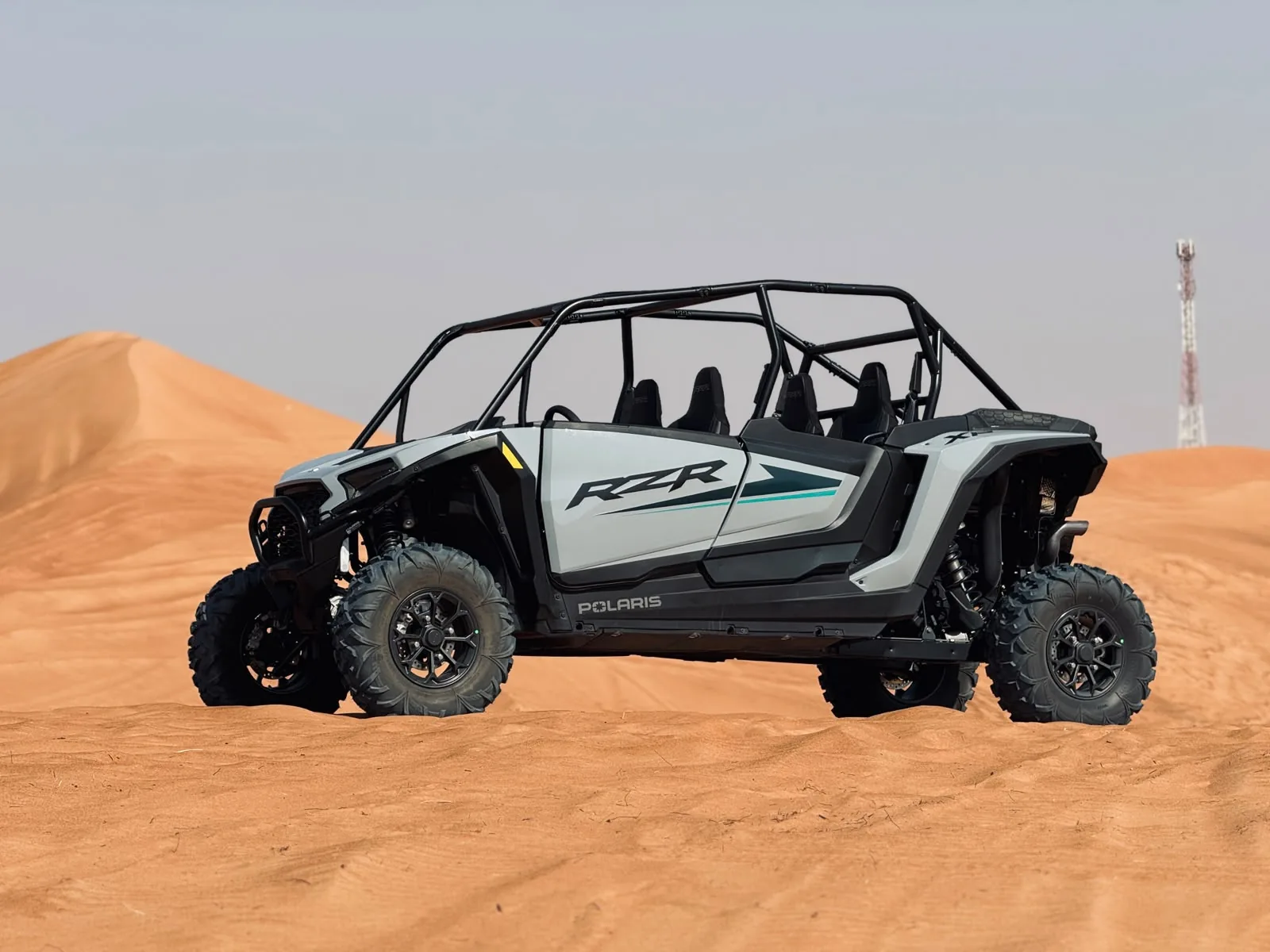 Polaris RZR four seater dune buggy parked on a red dune ridge in Dubai