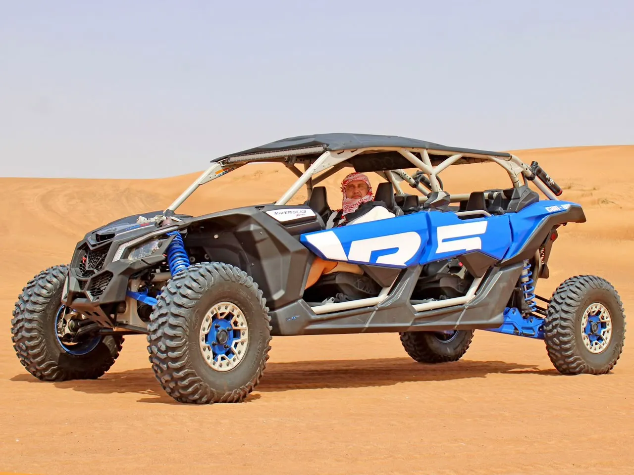 Couple in a Can-Am Maverick X3 4-seater dune buggy in the Dubai desert