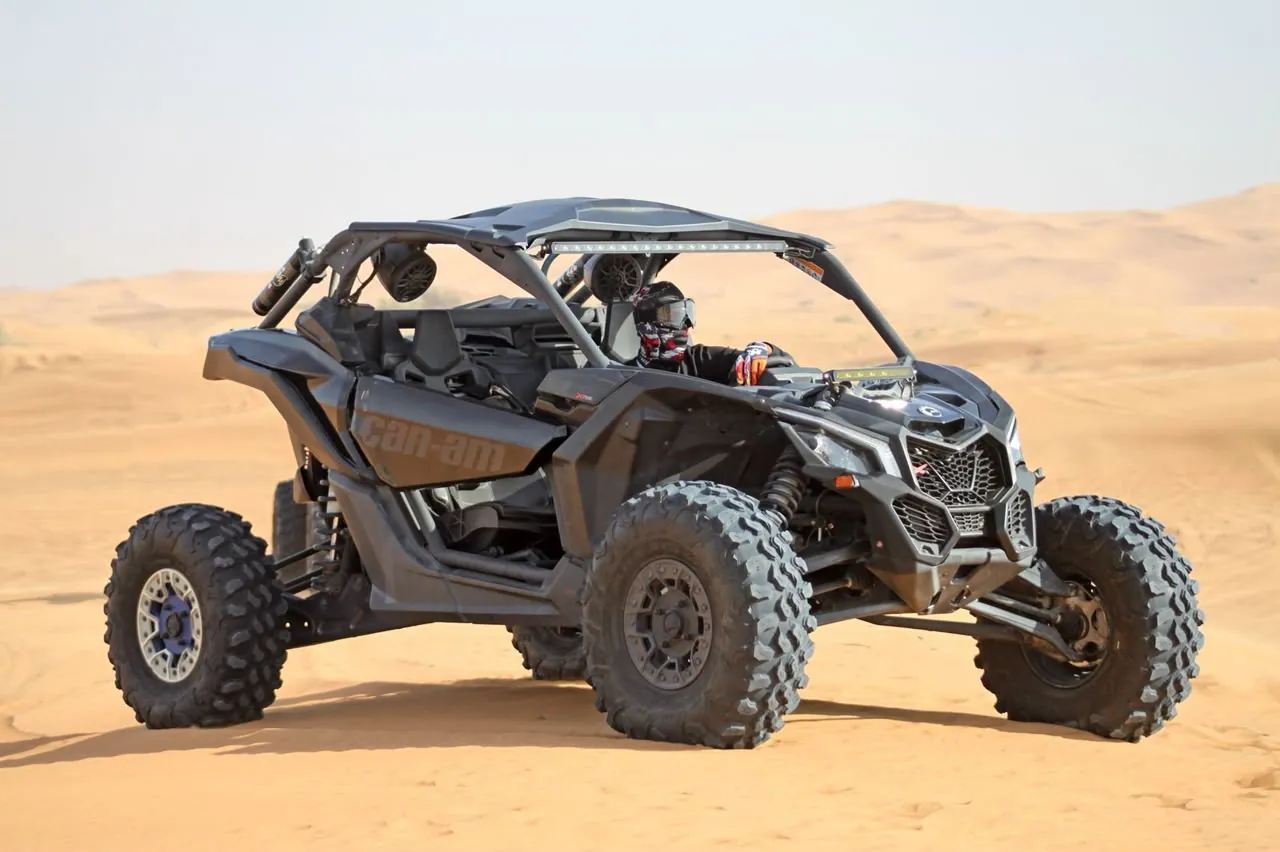 Black Can-Am Maverick X3 2-seater dune buggy on a Dubai red dune