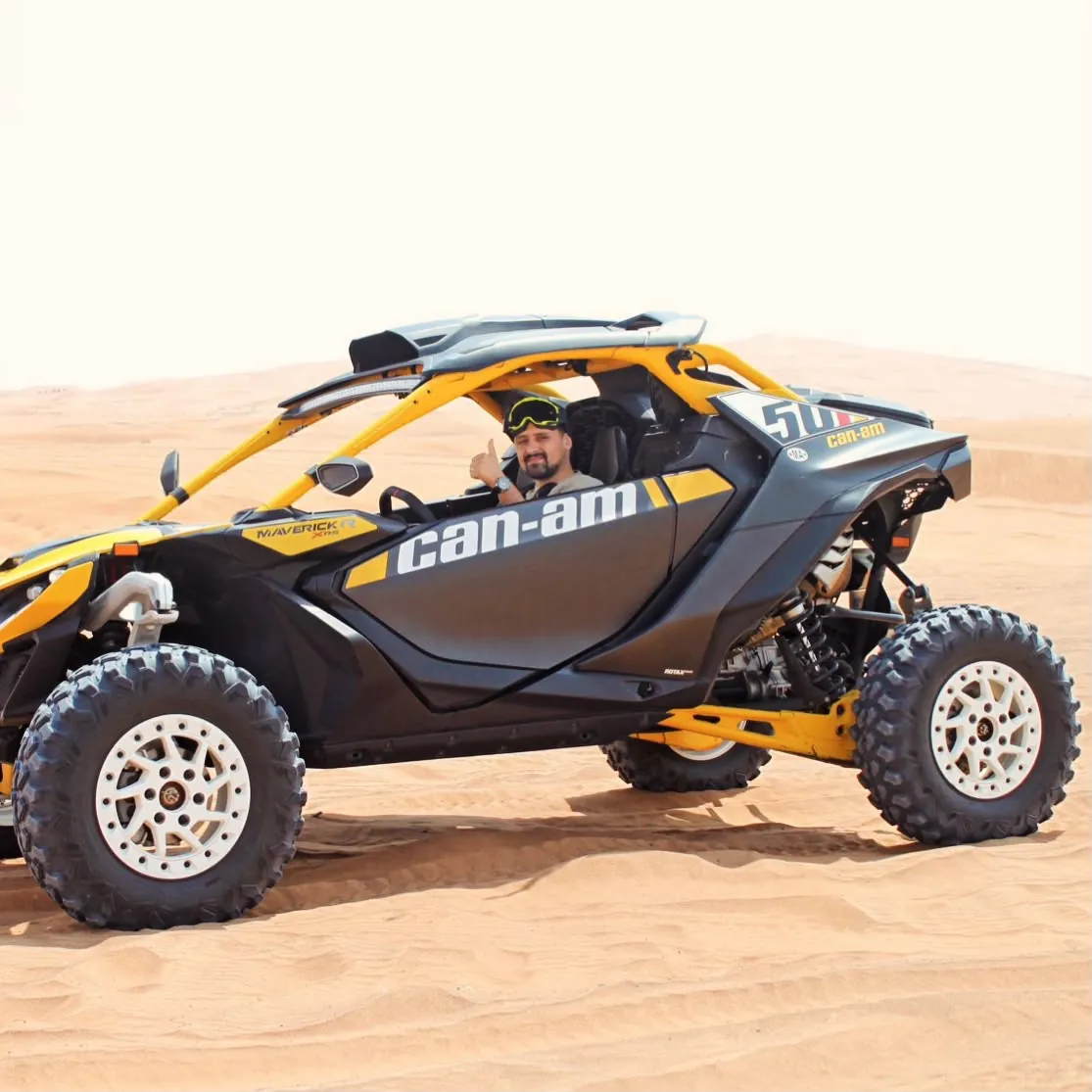 Yellow Can-Am Maverick X3 turbo dune buggy driving across Dubai sand