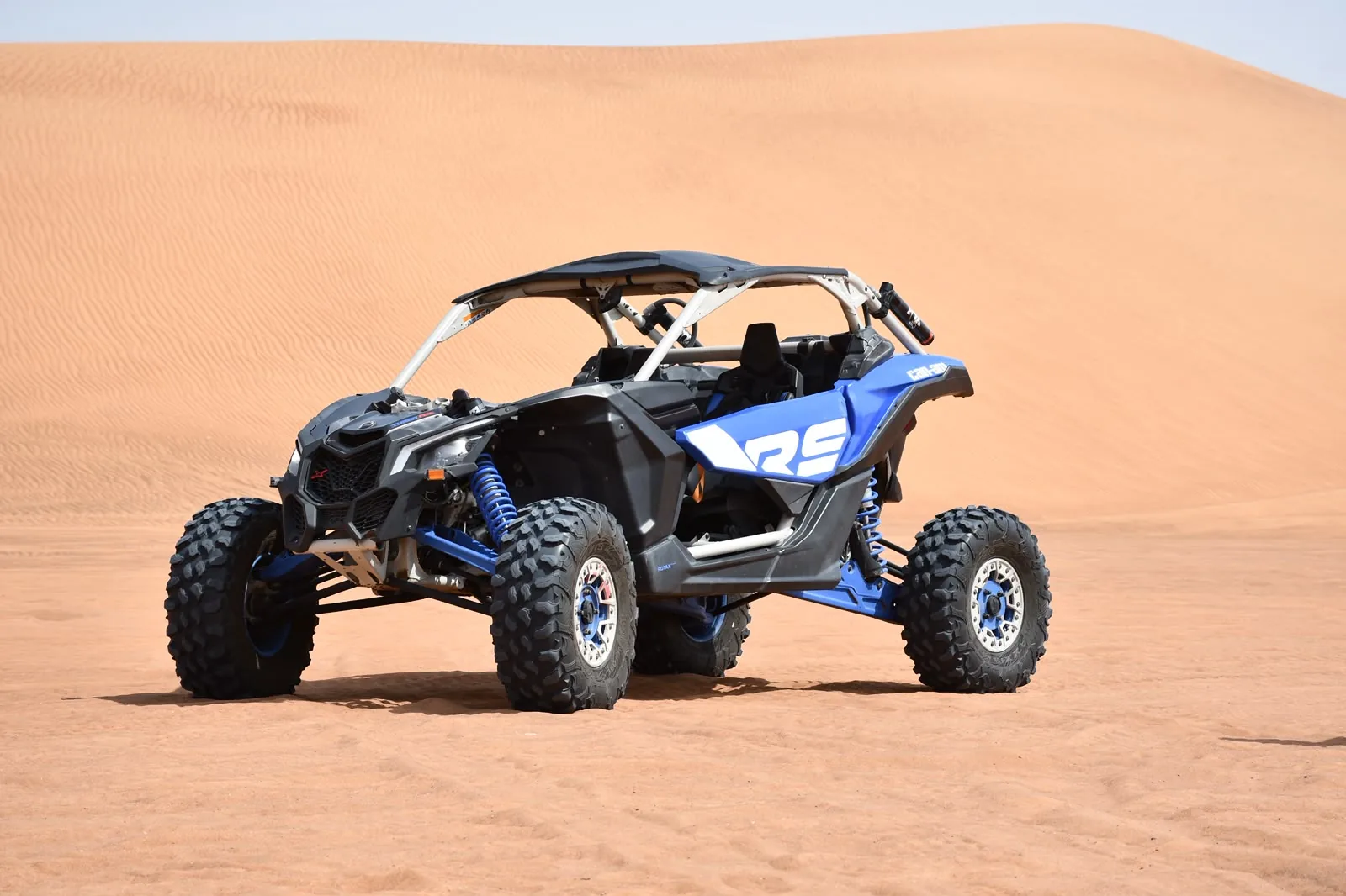 Blue Can-Am Maverick R two seater dune buggy on a Dubai red dune