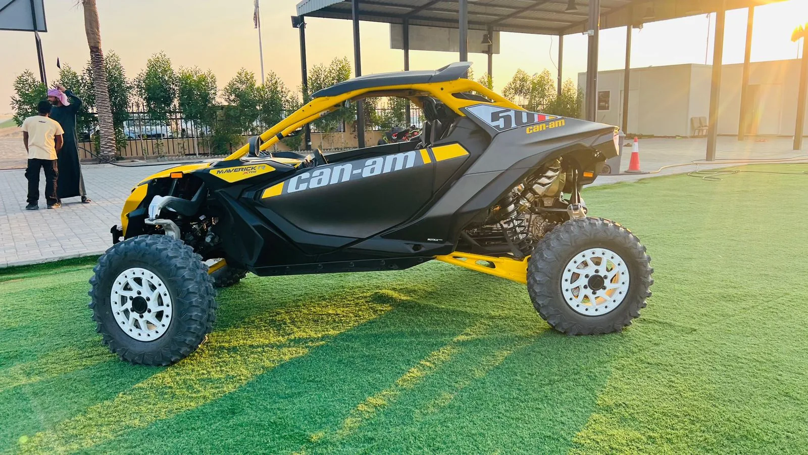 Yellow Can-Am Maverick R dune buggy under the shade canopy at the Al Awir base