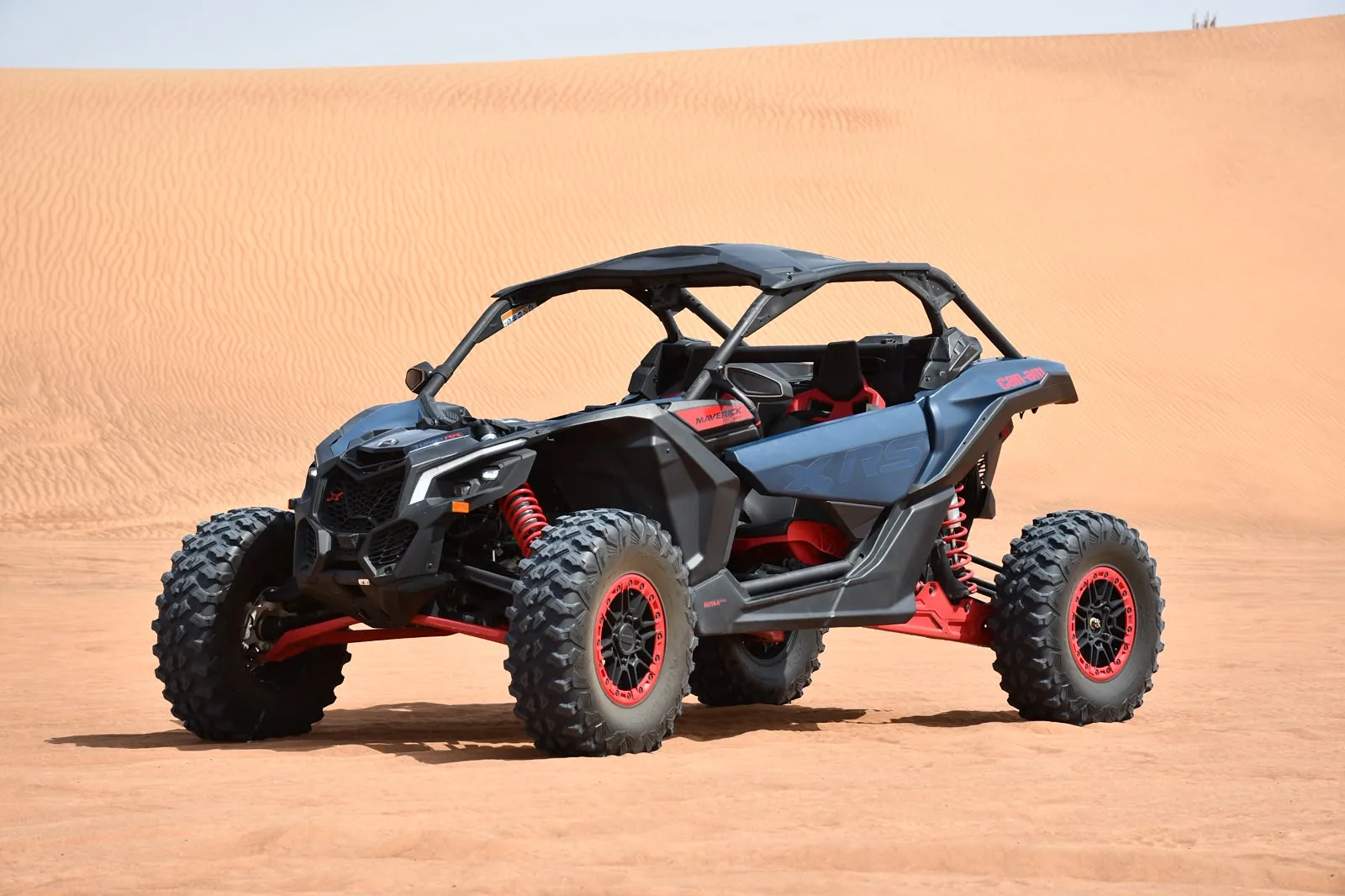 Black and red Can-Am Maverick X3 dune buggy on the Dubai red dunes