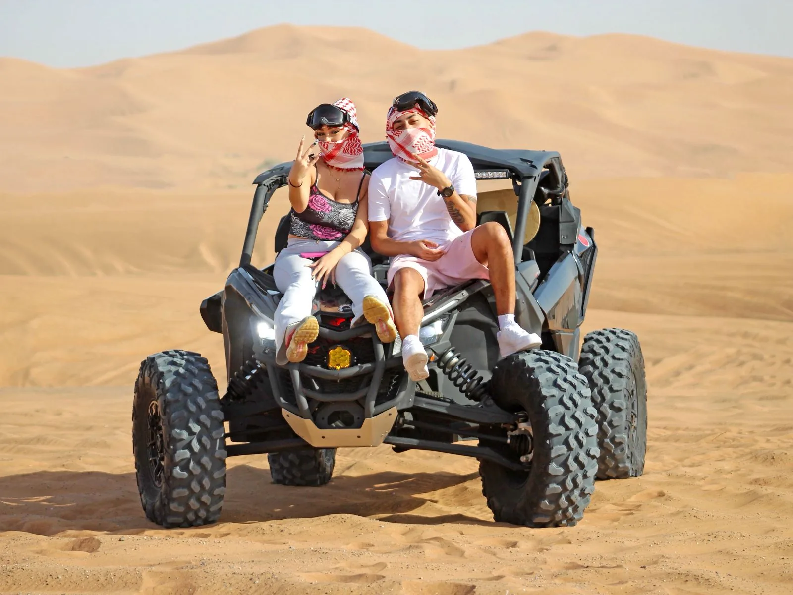 Couple sitting on a Can-Am dune buggy at a photo stop in the Dubai desert