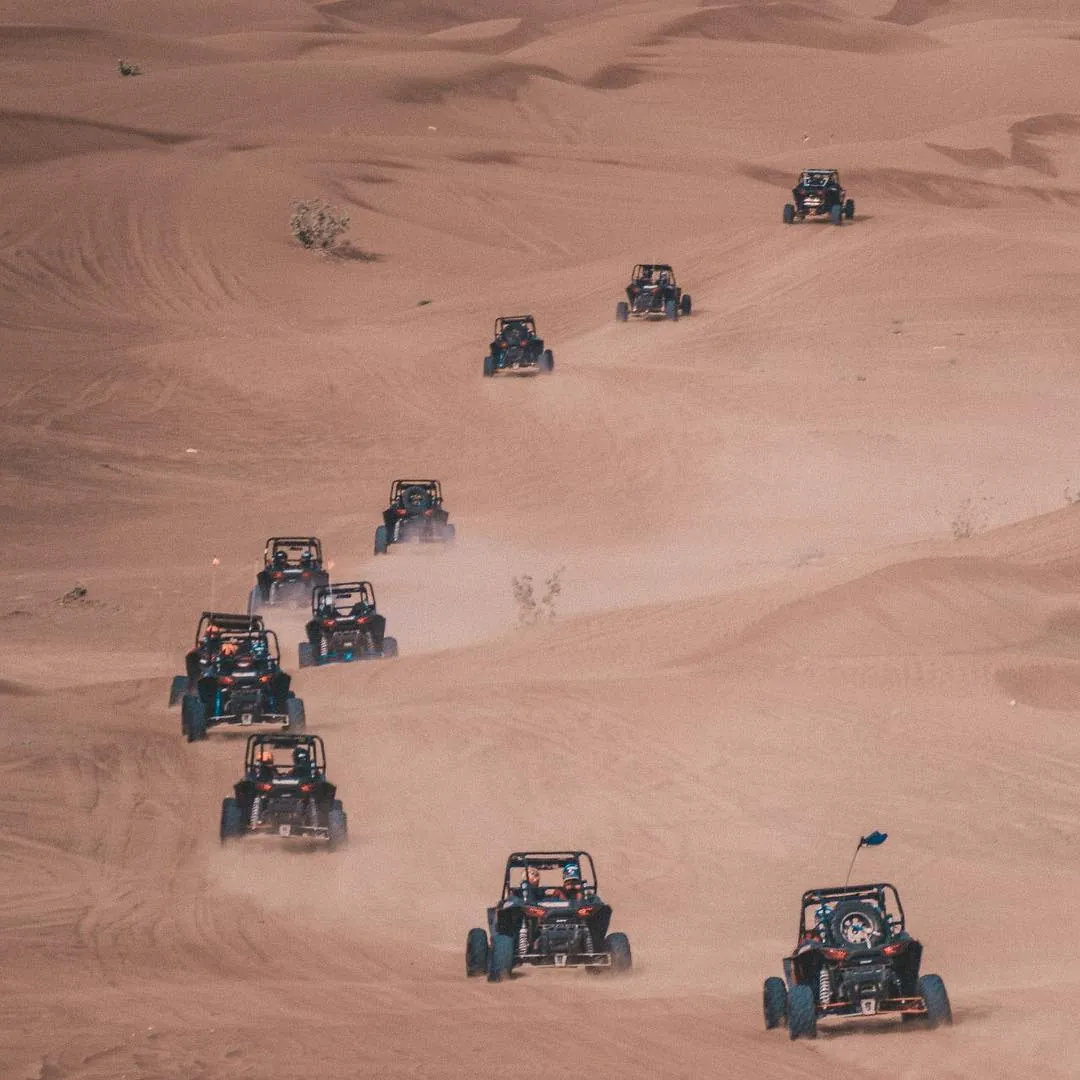 Convoy of dune buggies crossing the red dunes on a Dubai desert tour