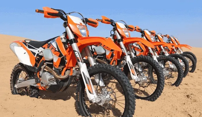 Row of orange KTM dirt bikes prepared for a guided desert ride in Dubai