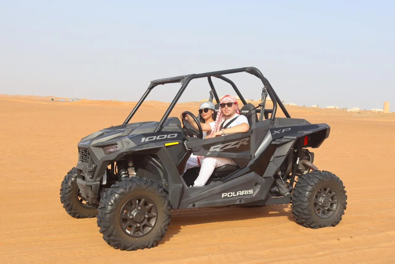 Polaris RZR 1000 2-seater dune buggy with riders in the Dubai desert