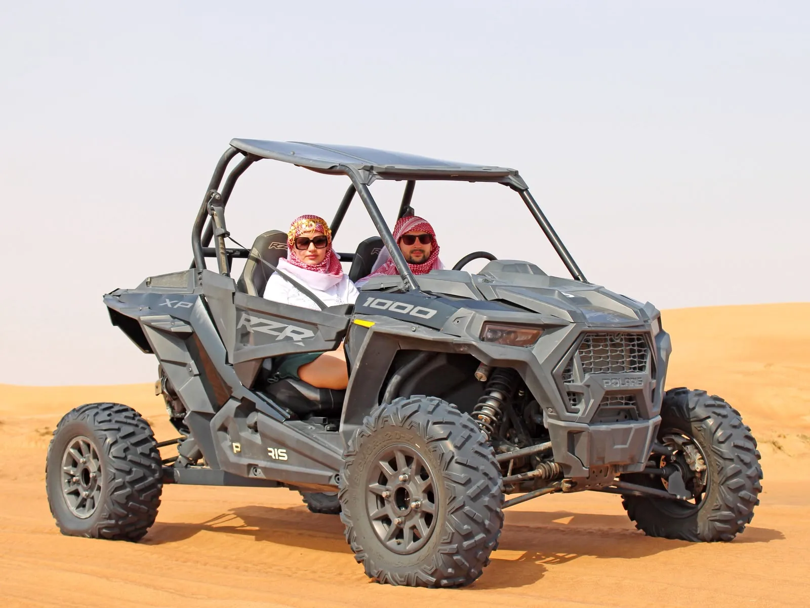 Two guests in a Polaris RZR 1000 dune buggy during a Dubai desert ride