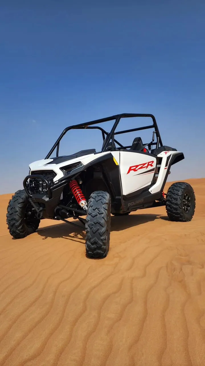 White Polaris RZR Pro dune buggy on Dubai desert sand