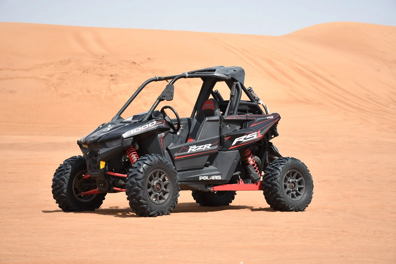 Black Polaris RZR RS two seater dune buggy on the Dubai red dunes
