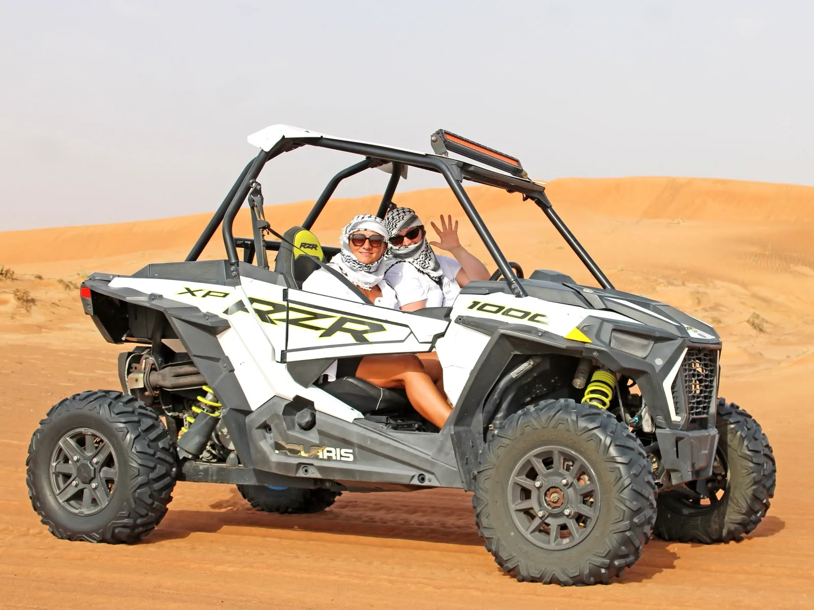 Guests waving from a Polaris RZR XP 1000 dune buggy on the Dubai red dunes