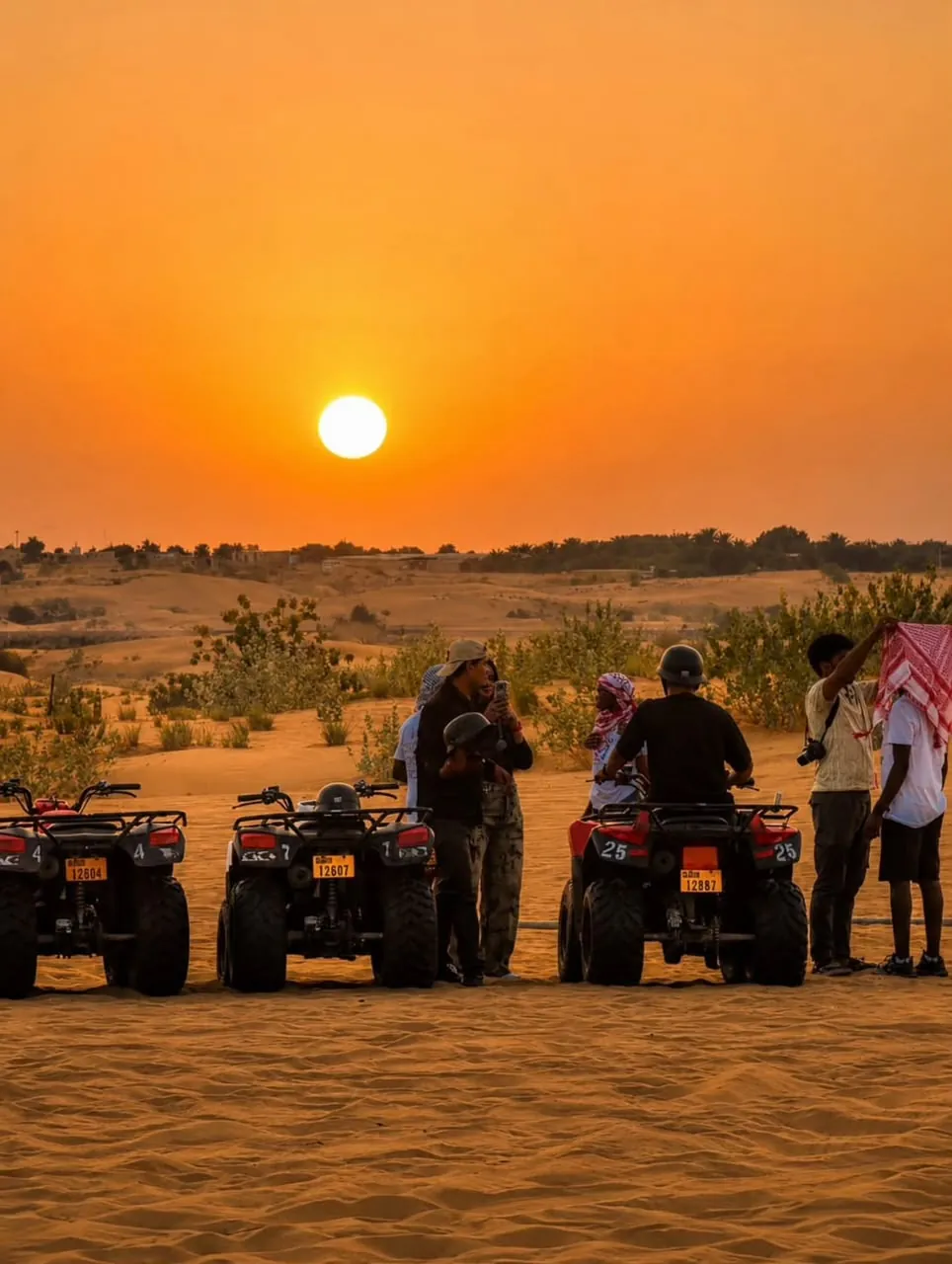 Quad bikes and guests silhouetted at sunset on a Dubai desert safari