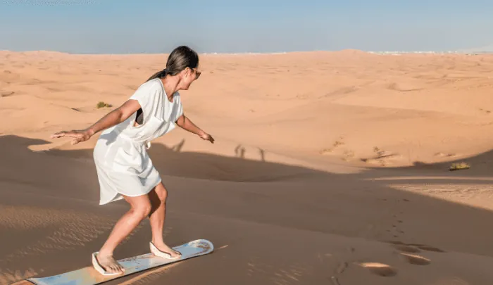 Guest sandboarding down a dune on a Dubai desert safari