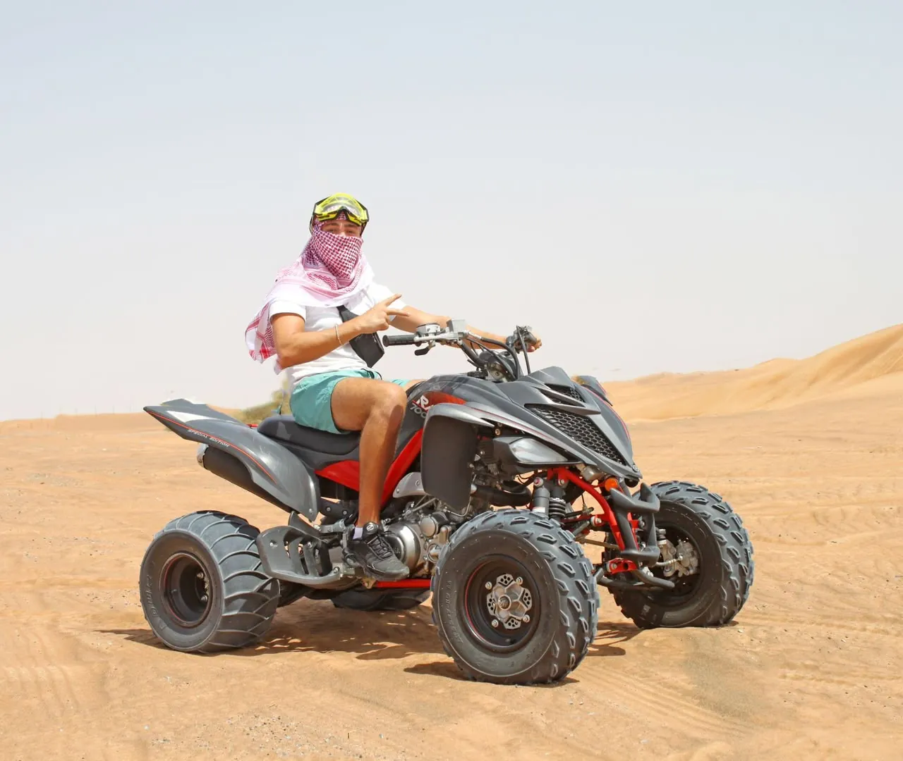 Rider on a Yamaha Raptor 700cc sport quad in the Lahbab red dunes, Dubai